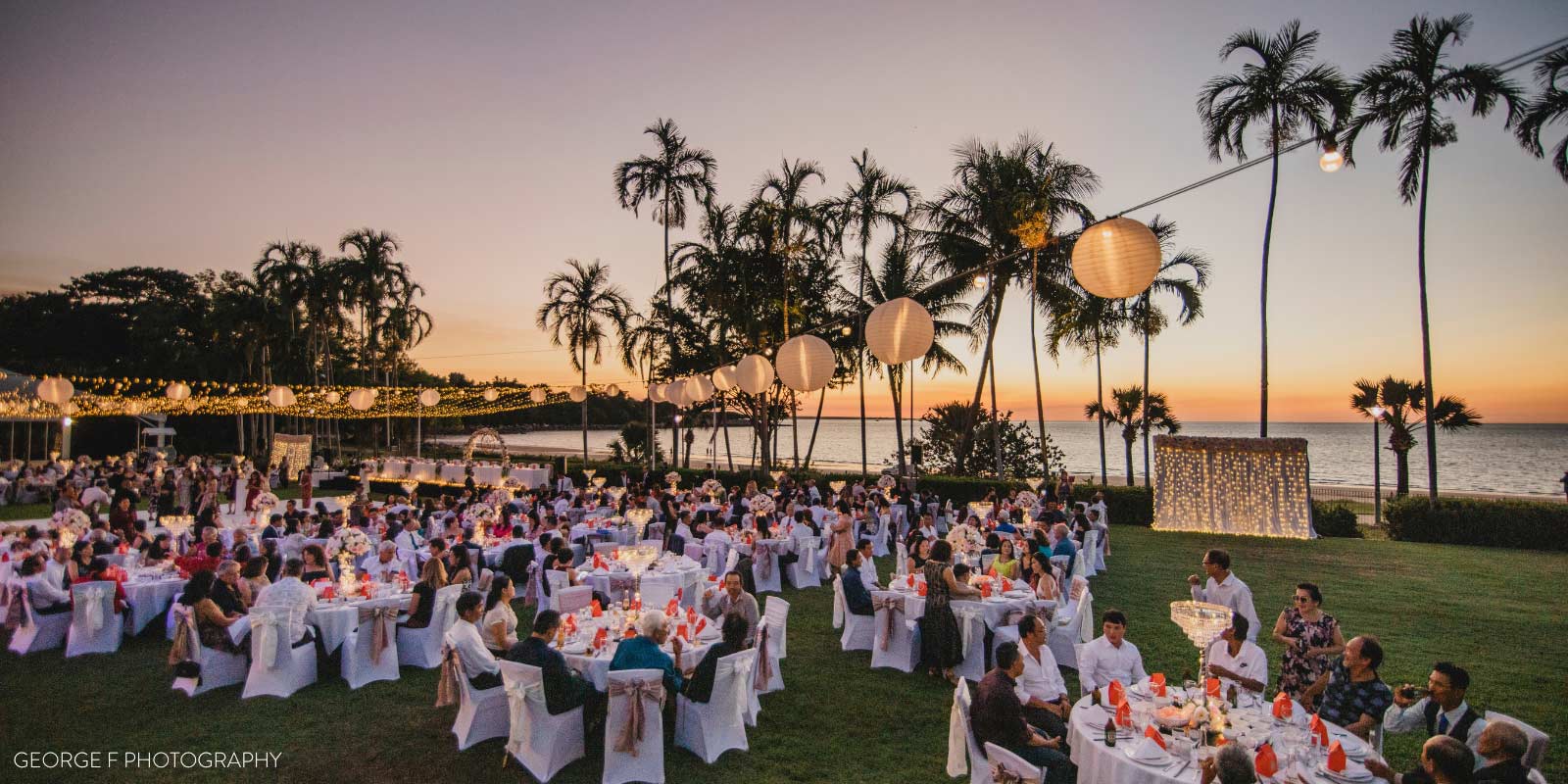 An outdoor event with string lights and tables at twilight.