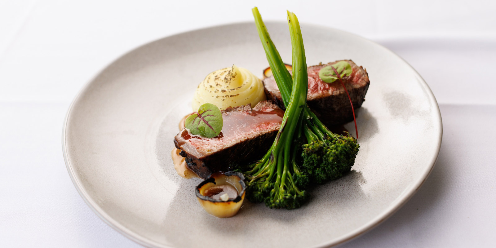 Steak and broccoli on a white plate.