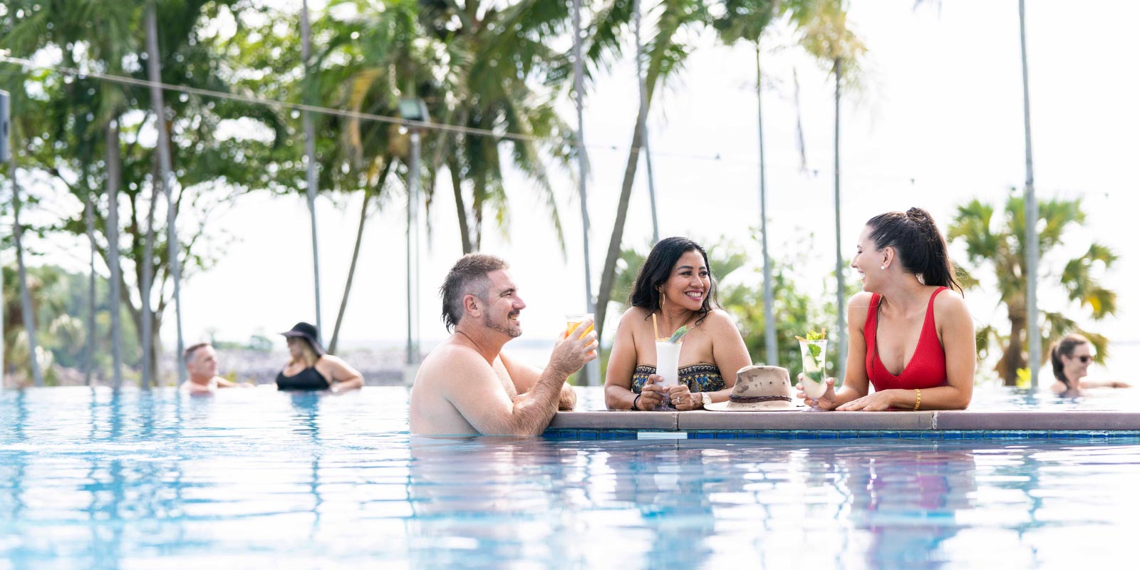 Group of people in the pool with drinks.