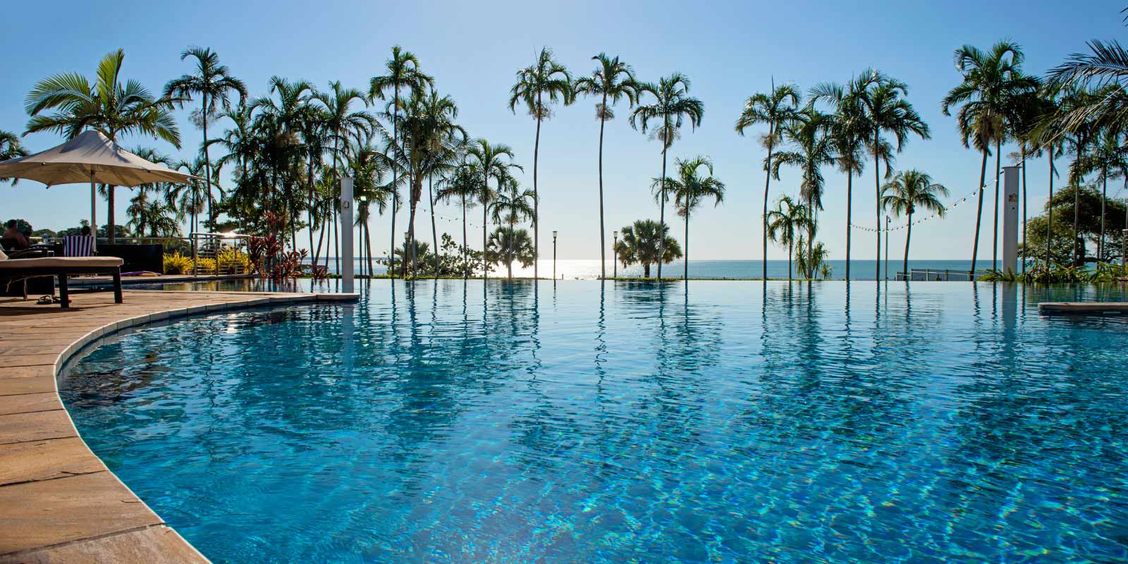 View of the pool with palm trees and deck with patio furniture.