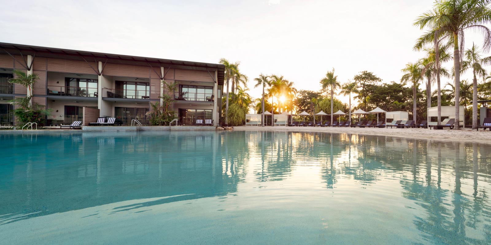 Shot of the pool next to the beach and villas at sunset