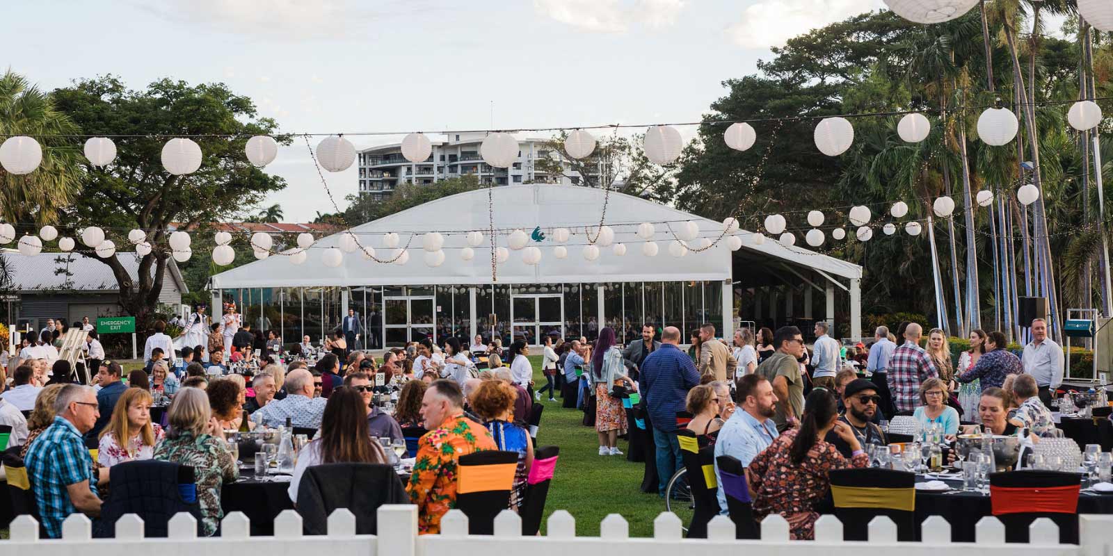 An event hosted outside with stringed lights and tents.